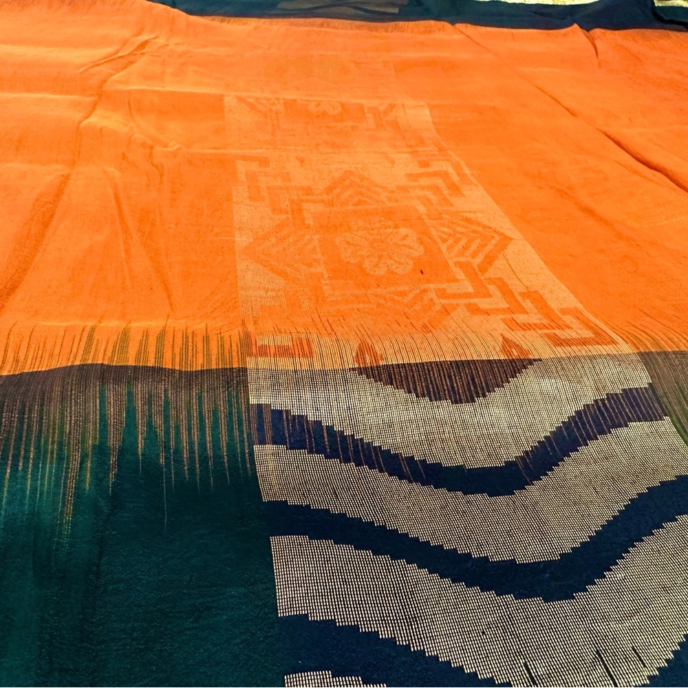 Vibrant orange pure silk saree with dark green and black border.